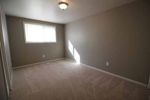 spare room with light carpet and baseboards