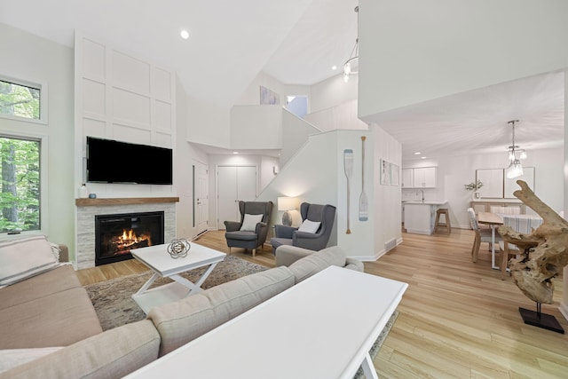 9773 Weko Dr, Bridgman, MI 49106 - living room with a glass covered fireplace, light wood-type flooring, a towering ceiling, baseboards, and recessed lighting