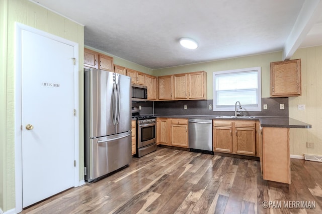 8220 Indian Shores Dr, Howard City, MI 49329 - kitchen with stainless steel appliances, a sink, dark countertops, dark wood finished floors, and tasteful backsplash