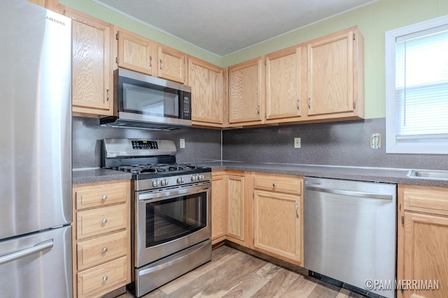 8220 Indian Shores Dr, Howard City, MI 49329 - kitchen featuring stainless steel appliances, light brown cabinets, dark countertops, light wood-style floors, and crown molding
