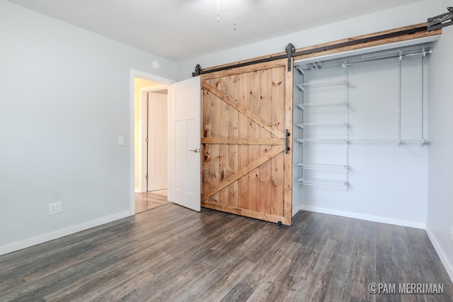 8220 Indian Shores Dr, Howard City, MI 49329 - unfurnished bedroom featuring wood finished floors, a barn door, and baseboards