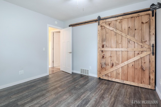 8220 Indian Shores Dr, Howard City, MI 49329 - unfurnished bedroom featuring a barn door, wood finished floors, and baseboards