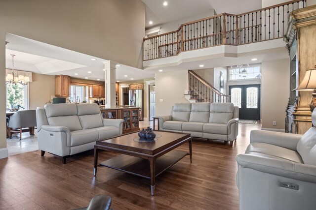 4624 Parman Rd, Stockbridge, MI 49285 - living room with decorative columns, a chandelier, a towering ceiling, dark wood-type flooring, and baseboards