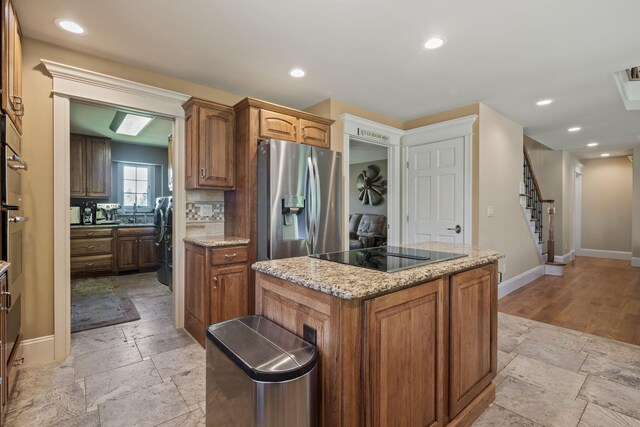 4624 Parman Rd, Stockbridge, MI 49285 - kitchen with stainless steel refrigerator with ice dispenser, black electric cooktop, stone tile flooring, baseboards, and a kitchen island