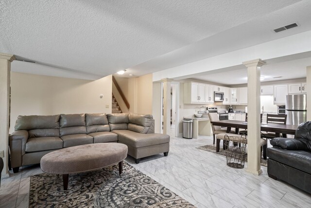 4624 Parman Rd, Stockbridge, MI 49285 - living room with decorative columns, stairs, light marble finish flooring, and a textured ceiling