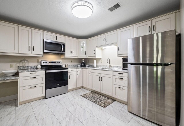 4624 Parman Rd, Stockbridge, MI 49285 - kitchen featuring appliances with stainless steel finishes, a sink, light marble finish flooring, light stone countertops, and glass insert cabinets