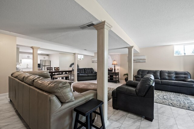 4624 Parman Rd, Stockbridge, MI 49285 - living room featuring light marble finish floors, a textured ceiling, and decorative columns