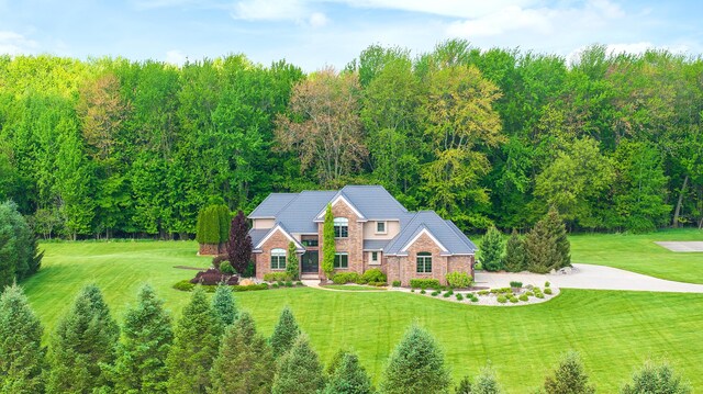 4624 Parman Rd, Stockbridge, MI 49285 - view of front of house with brick siding, a front yard, and a wooded view