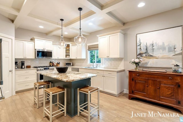 2078 Chippewa Dr Unit 25, Holland, MI 49424 - kitchen featuring appliances with stainless steel finishes, a kitchen breakfast bar, light wood-style floors, coffered ceiling, and tasteful backsplash