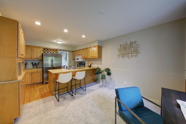 843 Greenhills Dr, Ann Arbor, MI 48105 - kitchen with stainless steel fridge, a peninsula, white microwave, a kitchen bar, and light countertops