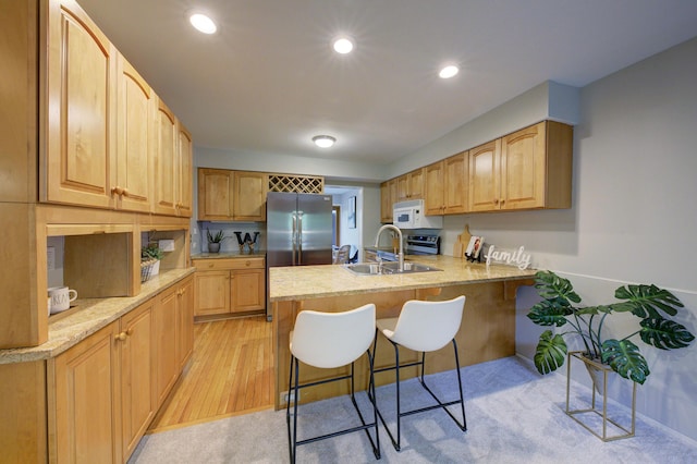 843 Greenhills Dr, Ann Arbor, MI 48105 - kitchen with white microwave, a peninsula, a sink, stainless steel refrigerator, and a kitchen breakfast bar