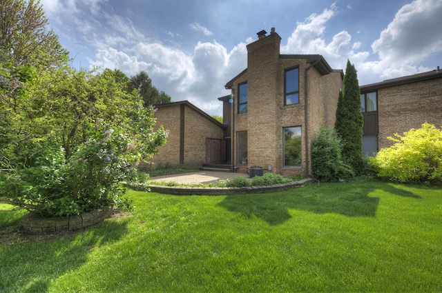 843 Greenhills Dr, Ann Arbor, MI 48105 - back of house with a chimney, a lawn, and brick siding