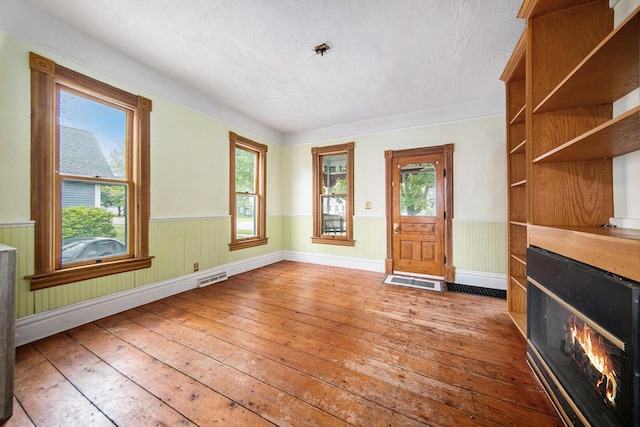 237 E Main St, Milan, MI 48160 - entrance foyer featuring light wood finished floors, wainscoting, a textured ceiling, healthy amount of natural light, and a lit fireplace