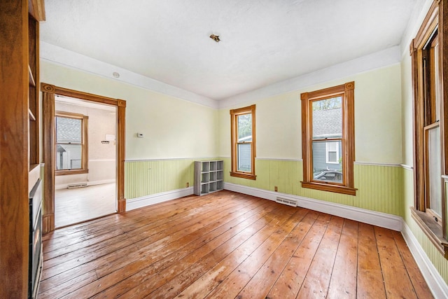 237 E Main St, Milan, MI 48160 - empty room featuring light wood-style flooring, baseboards, and a wainscoted wall