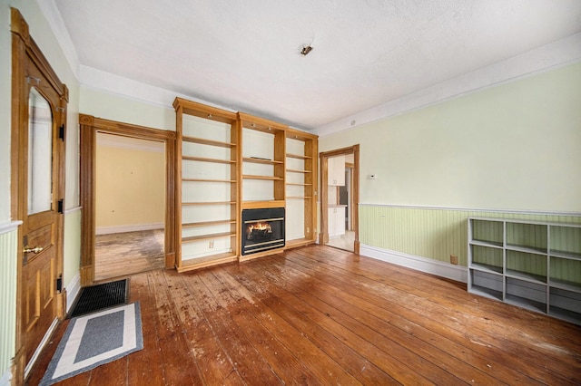 237 E Main St, Milan, MI 48160 - unfurnished living room featuring a glass covered fireplace, wood-type flooring, and wainscoting