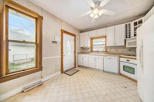 237 E Main St, Milan, MI 48160 - kitchen with white appliances, light floors, white cabinetry, a sink, and wallpapered walls