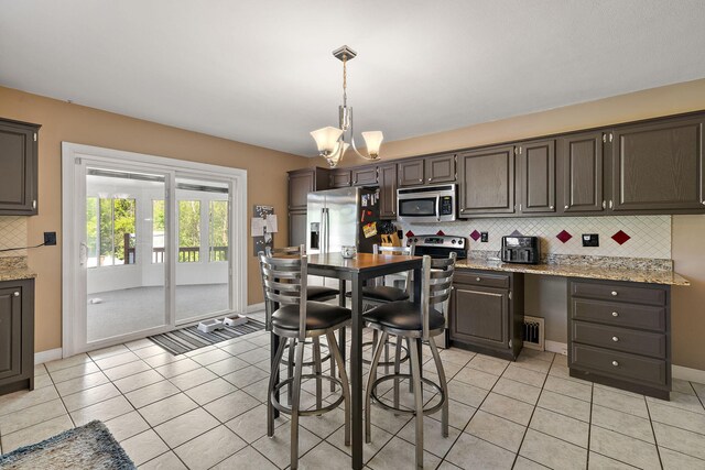 17270 Taft Rd, Spring Lake, MI 49456 - kitchen featuring appliances with stainless steel finishes, backsplash, light tile patterned floors, and a chandelier