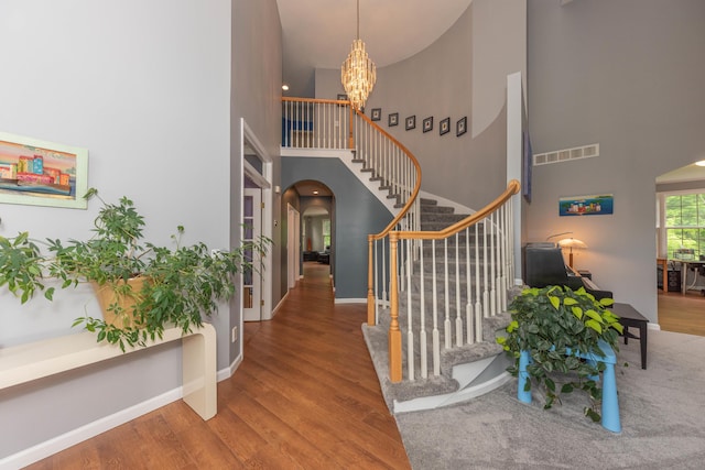 1218 Waterways Dr, Ann Arbor, MI 48108 - foyer entrance with arched walkways, a high ceiling, stairs, wood finished floors, and a chandelier