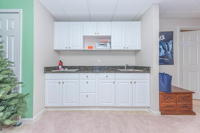 1218 Waterways Dr, Ann Arbor, MI 48108 - kitchen featuring a paneled ceiling, a sink, light colored carpet, white cabinetry, and baseboards