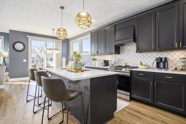 821 Janelle Ct, Portage, MI 49024 - kitchen featuring gas range, custom range hood, backsplash, light countertops, and a breakfast bar
