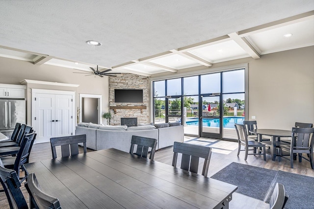 821 Janelle Ct, Portage, MI 49024 - dining room with beamed ceiling, a stone fireplace, a ceiling fan, coffered ceiling, and a textured ceiling