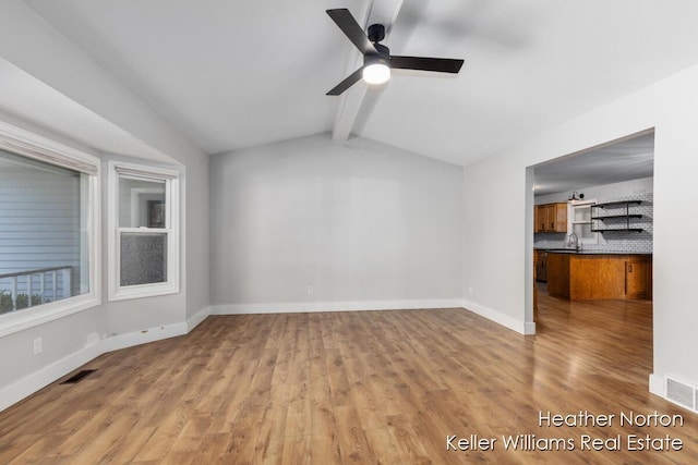 unfurnished living room featuring wood finished floors, a ceiling fan, baseboards, and a sink