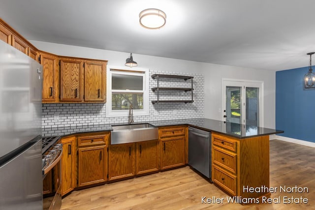 kitchen featuring stainless steel appliances, a peninsula, backsplash, and a sink