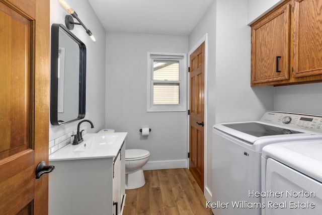 washroom with washer and clothes dryer, wood finished floors, and baseboards