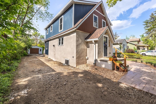 1435 Harpst St, Ann Arbor, MI 48104 - rear view of house with driveway, stucco siding, a detached garage, and an outdoor structure