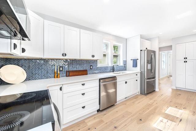 1435 Harpst St, Ann Arbor, MI 48104 - kitchen featuring stainless steel appliances, light wood-style flooring, light countertops, backsplash, and white cabinets