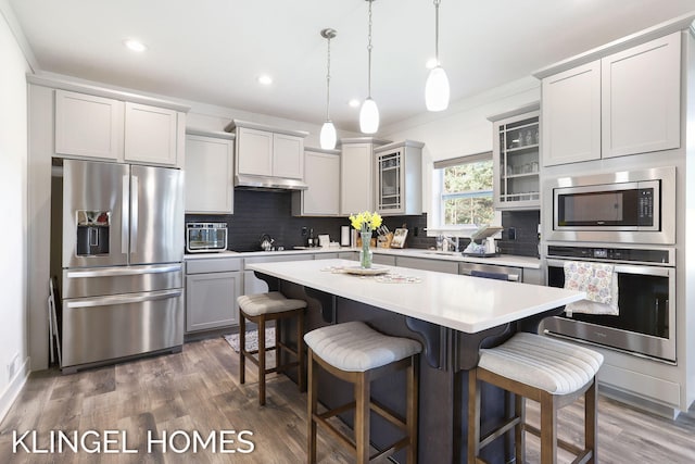 9235 Bigleaf Dr, West Olive, MI 49460 - kitchen with appliances with stainless steel finishes, a kitchen breakfast bar, a kitchen island, tasteful backsplash, and recessed lighting