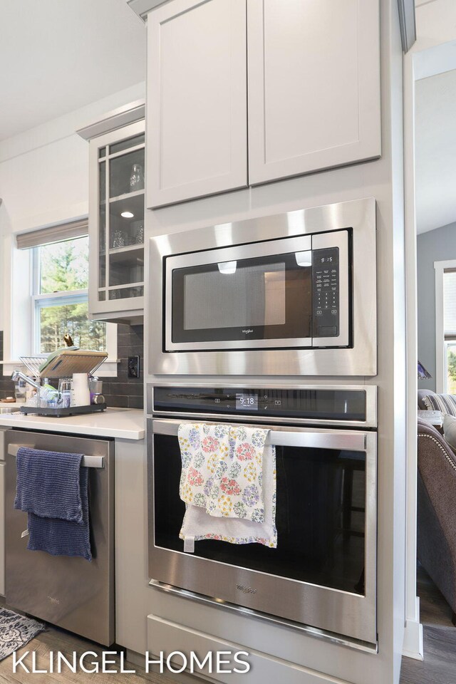 9235 Bigleaf Dr, West Olive, MI 49460 - kitchen with stainless steel appliances, light countertops, and glass insert cabinets