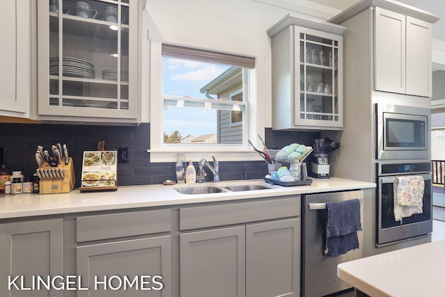 9235 Bigleaf Dr, West Olive, MI 49460 - kitchen featuring stainless steel appliances, a sink, tasteful backsplash, glass insert cabinets, and light countertops