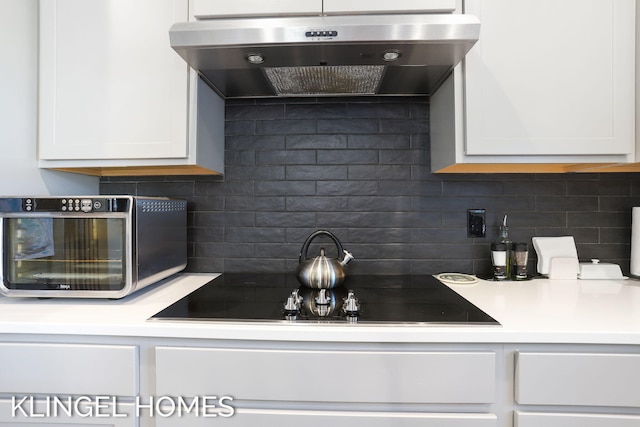 9235 Bigleaf Dr, West Olive, MI 49460 - kitchen featuring exhaust hood, backsplash, white cabinets, and black electric cooktop