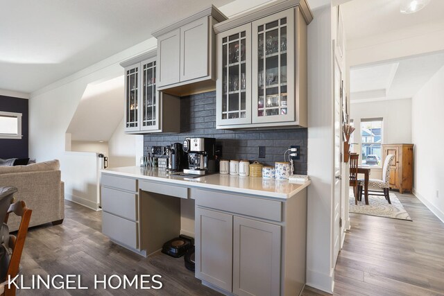 9235 Bigleaf Dr, West Olive, MI 49460 - kitchen with gray cabinets, dark wood-type flooring, tasteful backsplash, light countertops, and glass insert cabinets