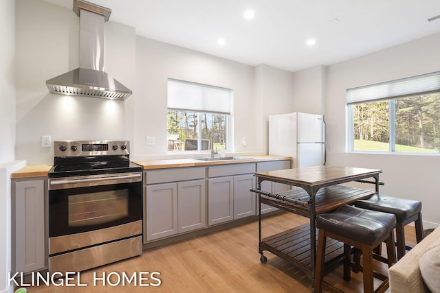 9235 Bigleaf Dr, West Olive, MI 49460 - kitchen featuring stainless steel range with electric stovetop, a sink, wall chimney exhaust hood, gray cabinetry, and plenty of natural light