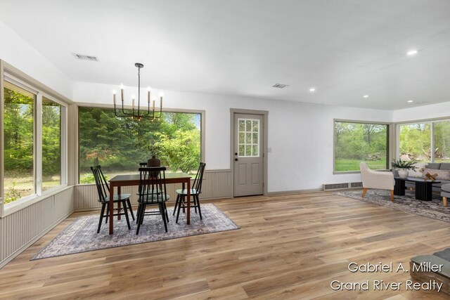 dining room with light wood finished floors, a chandelier, recessed lighting, and a wainscoted wall