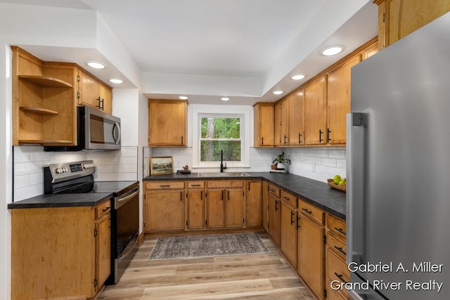 kitchen featuring appliances with stainless steel finishes, a sink, light wood-type flooring, open shelves, and recessed lighting