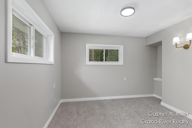 spare room featuring carpet flooring and baseboards