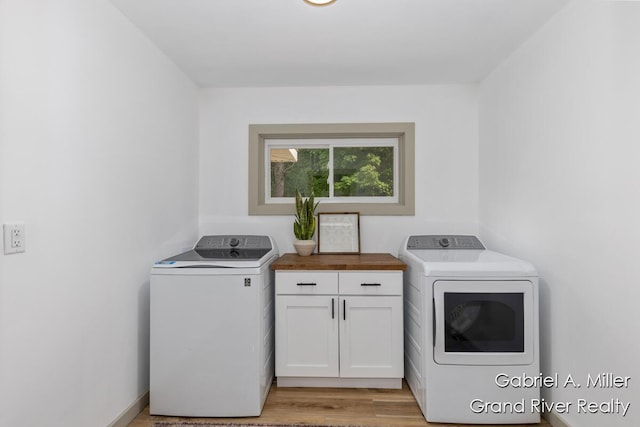 clothes washing area featuring cabinet space, washer and dryer, and light wood finished floors