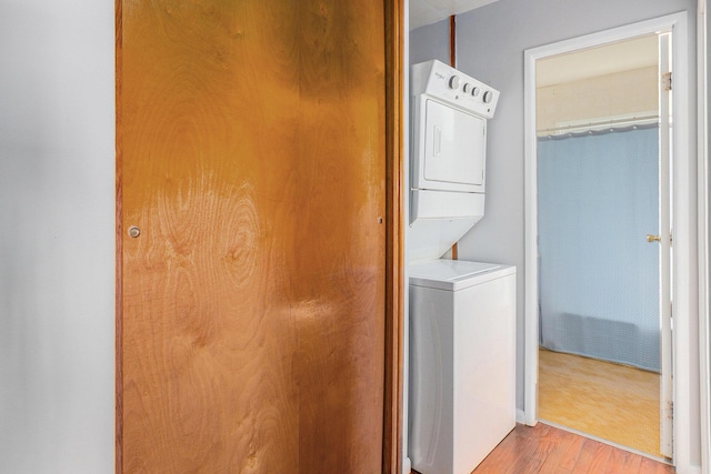 washroom featuring estacked washer and dryer and wood finished floors