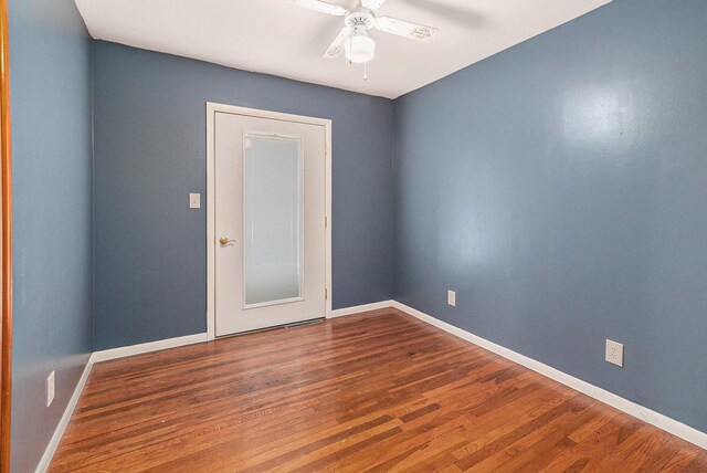 spare room featuring dark wood-style flooring, ceiling fan, and baseboards