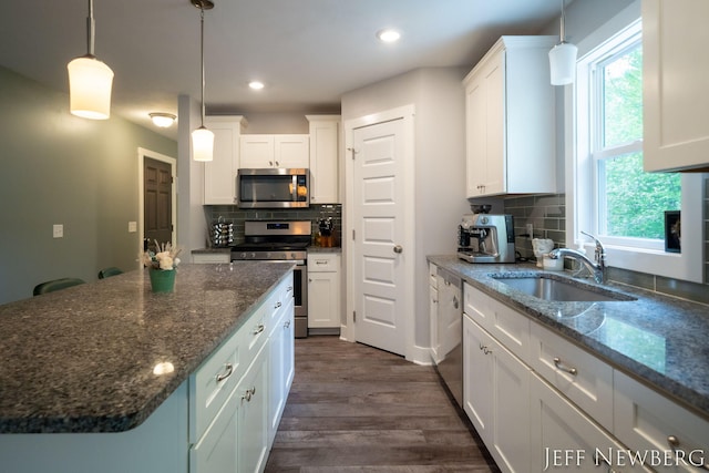 kitchen featuring appliances with stainless steel finishes, a sink, white cabinetry, dark wood-style flooring, and tasteful backsplash
