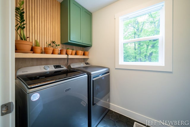 clothes washing area featuring cabinet space, washing machine and clothes dryer, dark tile patterned flooring, and baseboards