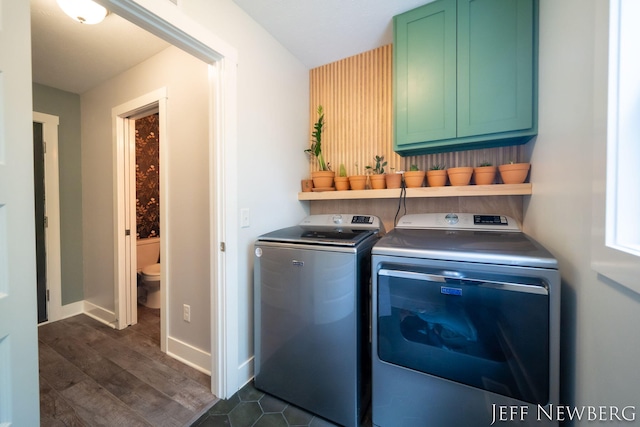 washroom featuring washing machine and dryer, cabinet space, dark wood-style flooring, and baseboards
