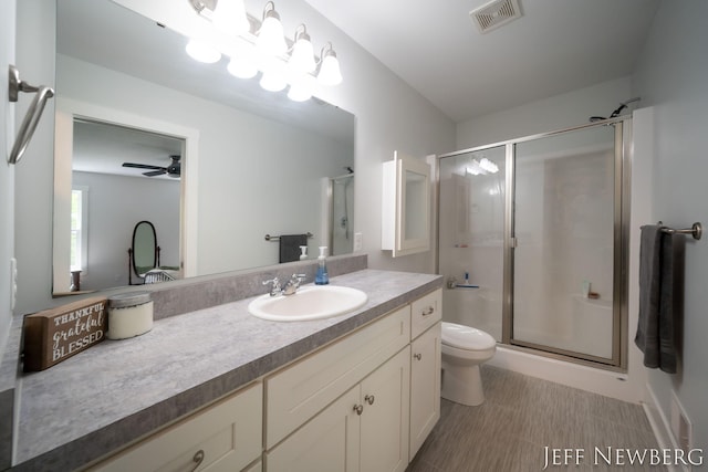 full bathroom featuring a stall shower, toilet, a ceiling fan, and vanity