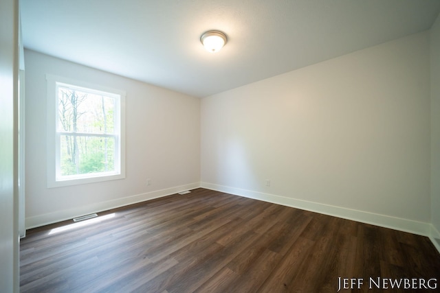 spare room with dark wood finished floors and baseboards