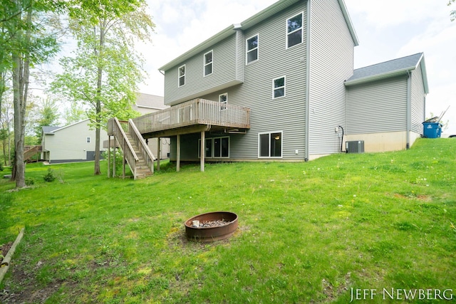 back of property with stairway, a wooden deck, an outdoor fire pit, and a yard