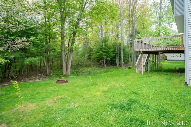 view of grassy yard with stairs and a deck