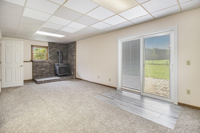 6001 Dover Ln, Traverse City, MI 49684 - unfurnished living room featuring a wood stove, a drop ceiling, baseboards, and carpet